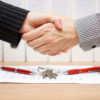 client and agent are handshaking over real estate contract and keys