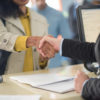 Customer shaking hands with bank teller at bank counter.